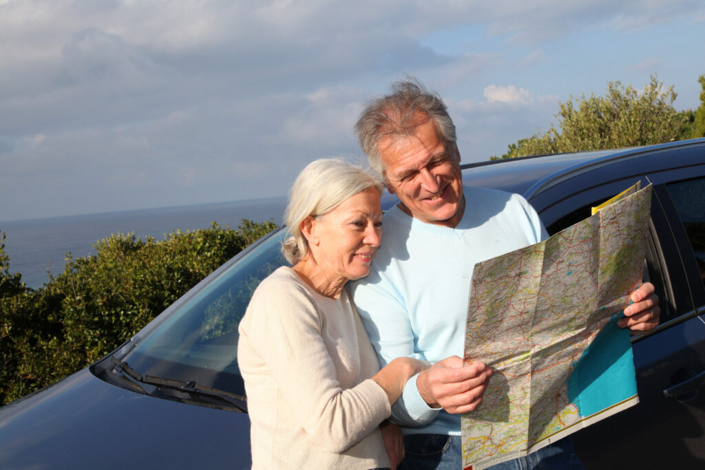 Senior couple looking at road map on car hood